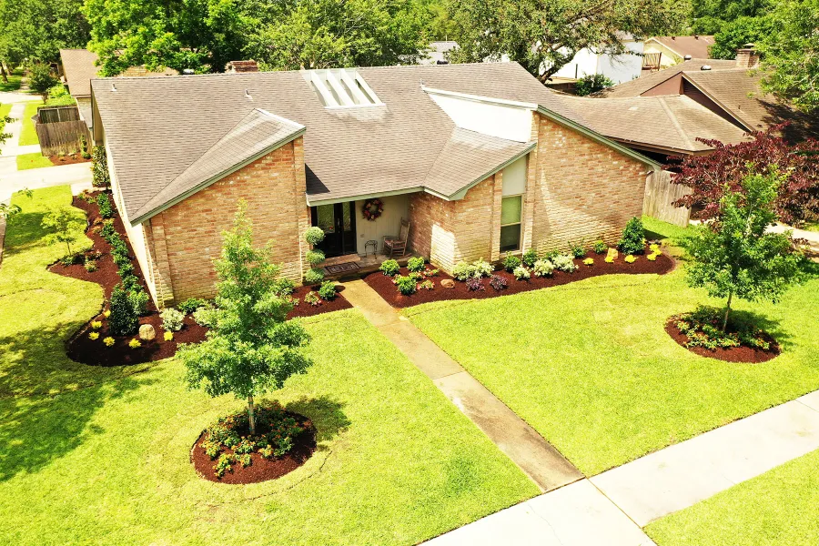 Layered planting beds and stone borders on a Katy front yard